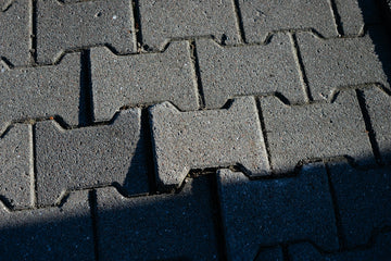 Grey interlocking concrete pavers on a walkway with sharp shadows